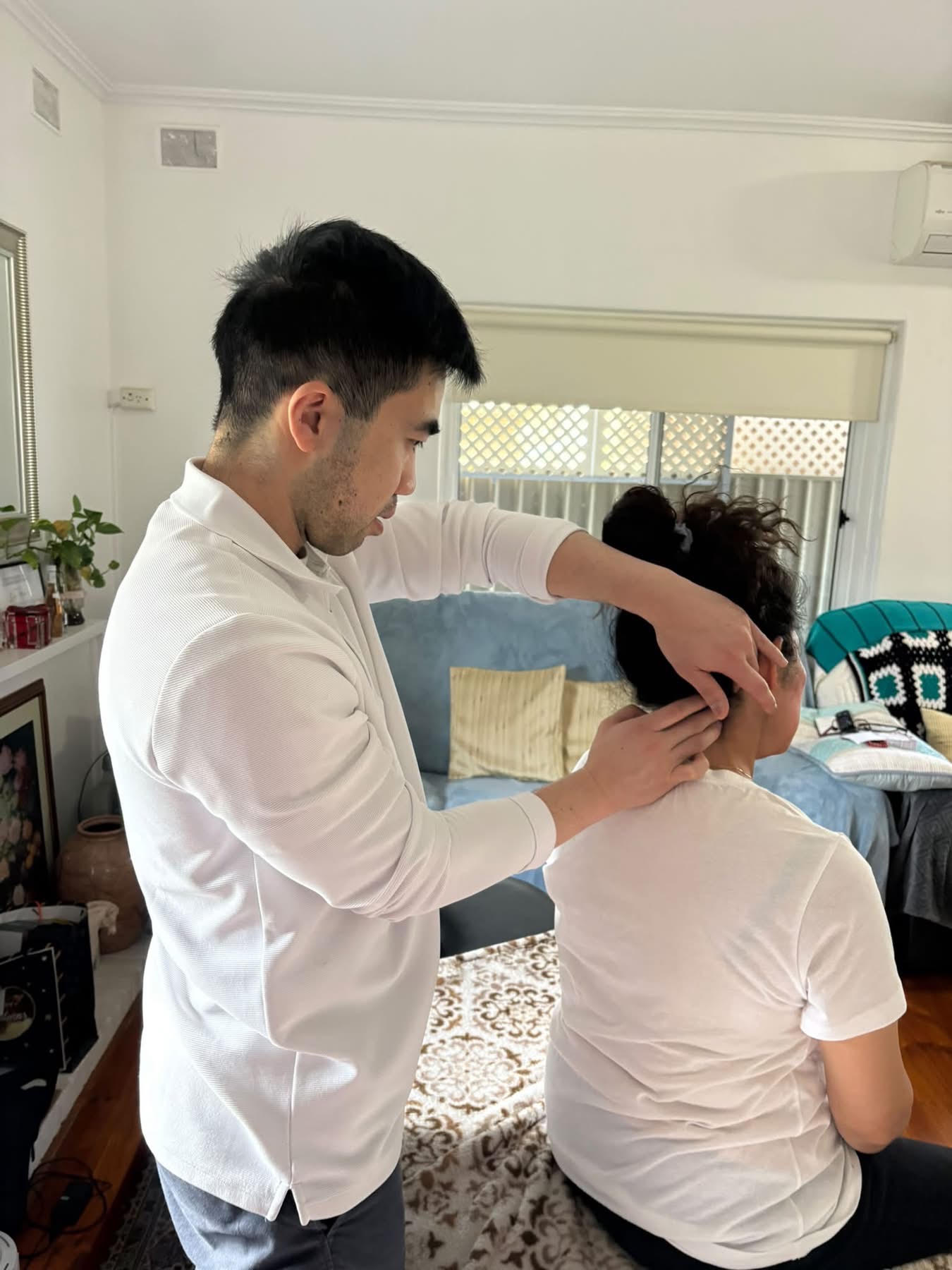 Philip Chau performing in-home neck treatment for client